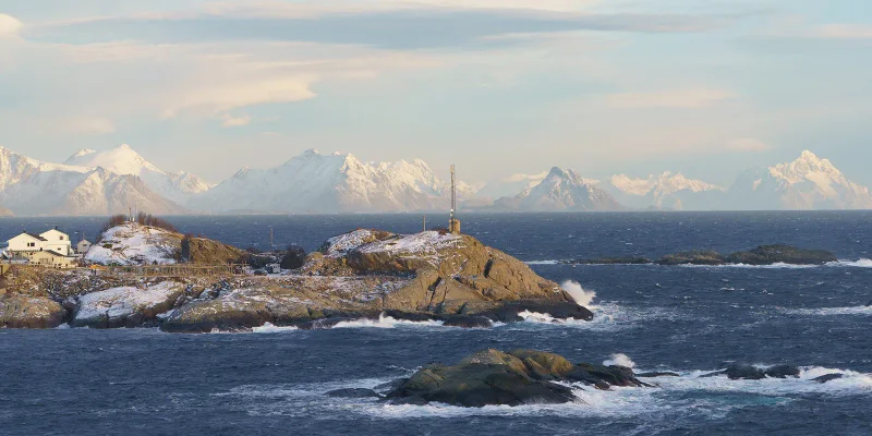 Felsinseln im Meer vor schneebedeckten Bergen