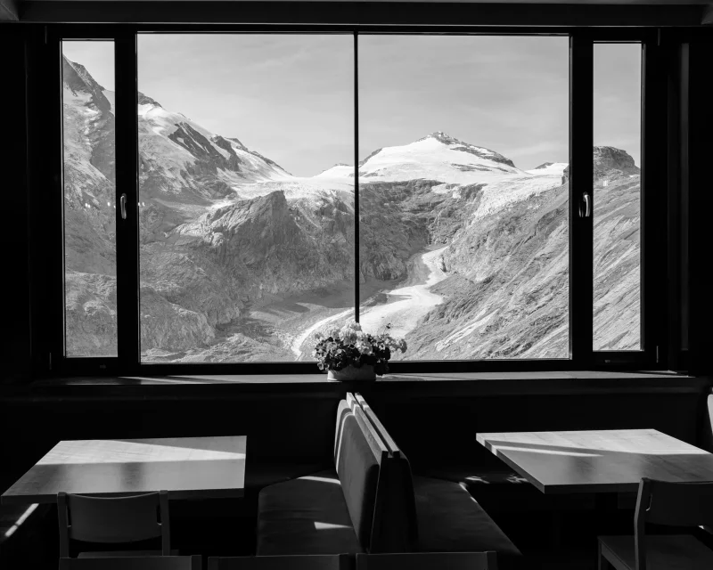 Blick durch ein Fenster auf schneebedeckte Berge