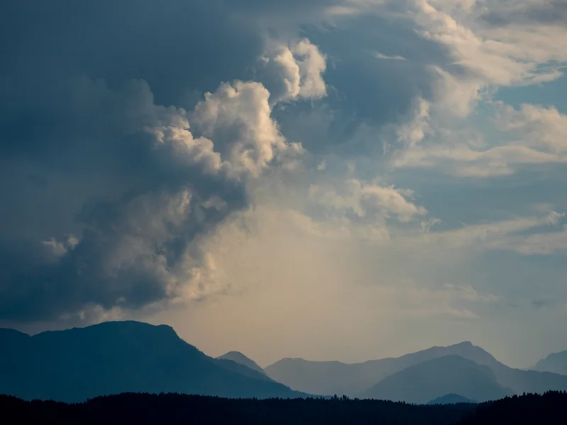 Sonnenlicht hinter Wolken über einem Bergtal